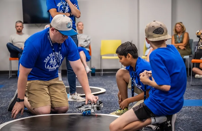 An instructor works with children during the coding summer camp.